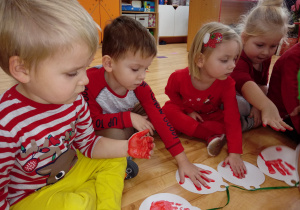 Dzieci odbijają rękę pomalowaną farbą na papierowej bombce